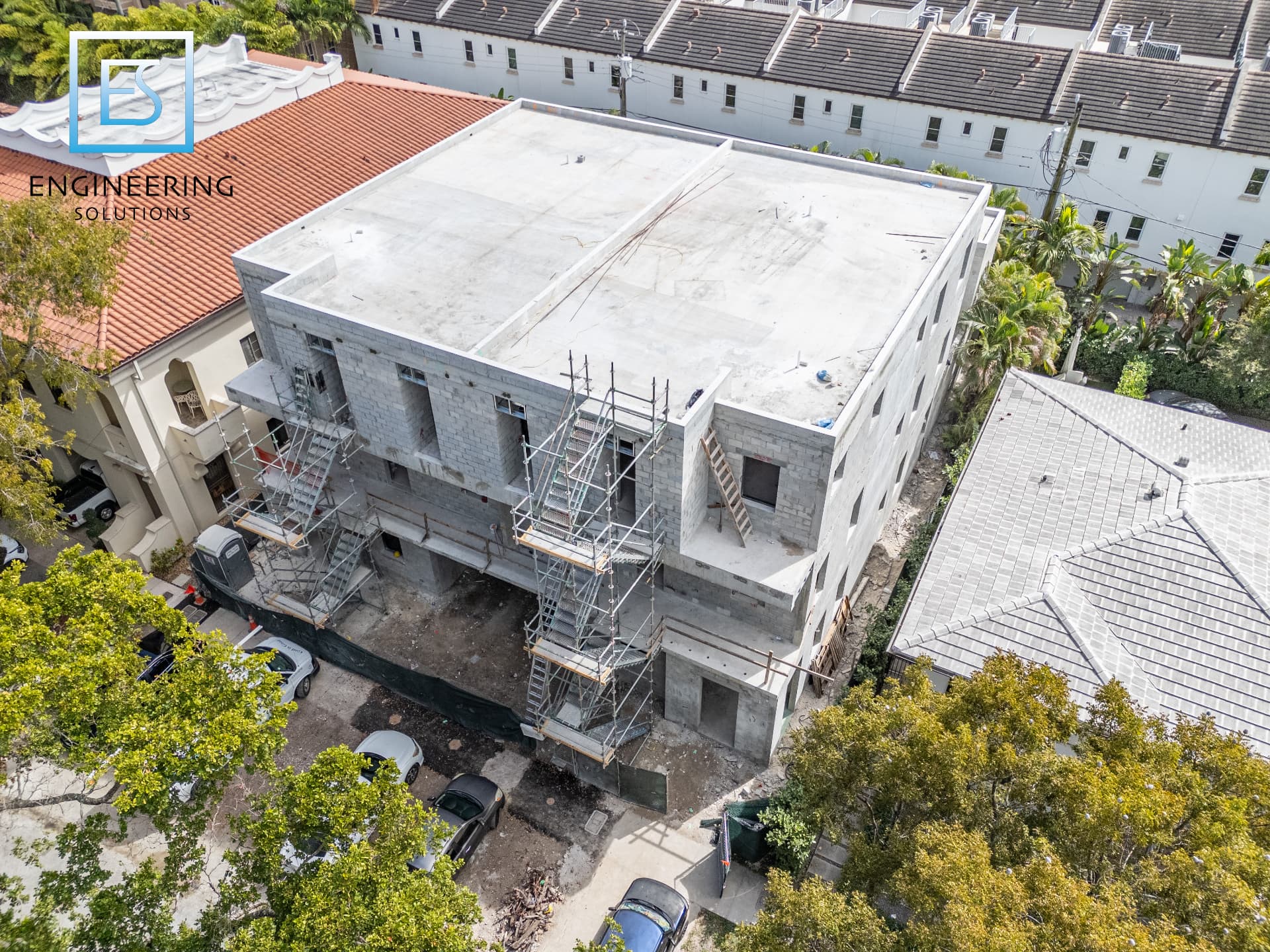 Three-story concrete and masonry structure topped out with exterior scaffolding at Malaga Townhomes in Coral Gables, Florida